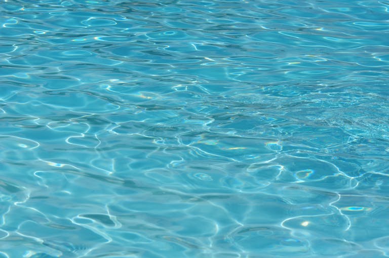 A vibrant turquoise water surface, showcasing clear ripples and captivating patterns. Perfect for summer themes.