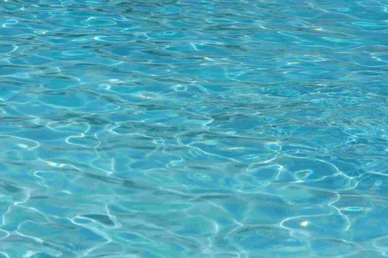 A vibrant turquoise water surface, showcasing clear ripples and captivating patterns. Perfect for summer themes.