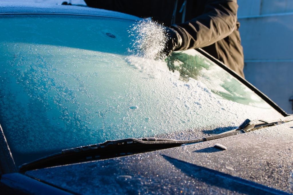 A man cleans frozen windshield by scratching